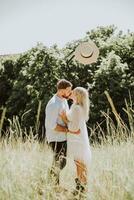 feliz e amoroso casal se beijando e jogando chapéu acima dentro verão foto