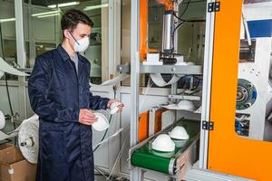 uma trabalhador carrinhos às a máquina dentro uma fábrica para a fabricação do médico máscaras com nanofibra. coronovírus e covid-19 proteção foto