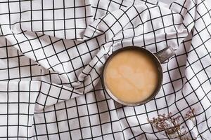 vida desacelerando baixa conceito. copo do café com leite em xadrez amassado tecido topo Visão foto