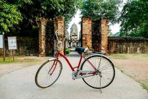 uma vermelho bicicleta estacionado dentro frente do a antigo têmpora foto