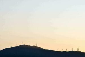 silhueta do vento turbinas às pôr do sol foto