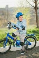 uma criança dentro uma capacete aprende para passeio uma bicicleta em uma ensolarado dia às pôr do sol foto
