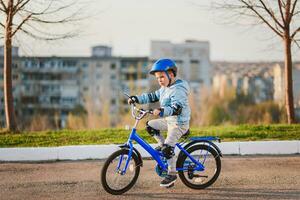 pequeno Garoto dentro capacete passeios uma bicicleta em uma ensolarado dia foto