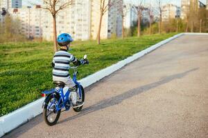 uma criança dentro uma capacete e proteção dentro uma bicicleta passeio em natureza dentro a Primavera foto