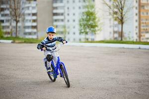 uma criança dentro uma capacete e proteção dentro uma bicicleta passeio em natureza dentro a Primavera foto