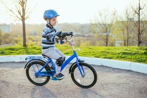 uma criança dentro uma capacete e proteção dentro uma bicicleta passeio em natureza dentro a Primavera foto