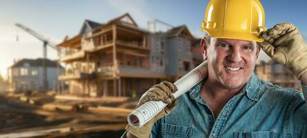 amigáveis masculino contratante às uma construção local vestindo uma Difícil chapéu e trabalhos luvas segurando dele projeto planos foto