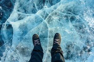 uma pé do turista em pé em a rachaduras superfície do congeladas lago baikal dentro a inverno estação do Sibéria, Rússia. foto