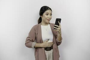 uma com fome ásia mulher empregado é segurando dela telefone e imaginando gostoso Comida ela quer para ordem, isolado em branco cor fundo. foto