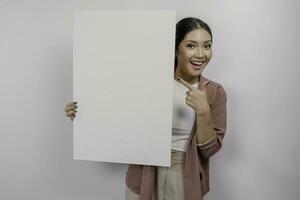 sorridente jovem ásia mulher empregado segurando e mostrando esvaziar em branco quadro, isolado de branco fundo foto