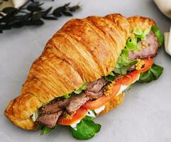 croissant com fervido carne de porco e tomates foto