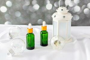 dois Cosmético garrafas com uma verde vidro pipeta com uma natural autocuidados produtos em uma Natal fundo com vidro bolas e uma lâmpada. bokeh luz foto