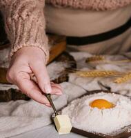 mulher mãos cortar uma fresco croissant e espalhando manteiga foto
