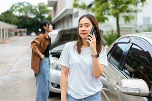 motorista de mulheres asiáticas verifica danos após um acidente de carro antes de tirar fotos e enviar seguro. reivindicação de seguro de acidente de carro on-line após o envio de fotos e evidências a uma companhia de seguros.