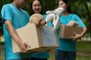 feliz jovem ásia alunos diverso voluntários aguarde doar caixa e brinquedos para caridade para compartilhar crianças e orfanatos, uma caridade para sustentabilidade. voluntário trabalhos estilo de vida e social cooperação foto