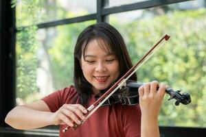 a atraente mulher Aprendendo músico tocam a violino às lar. compositor criando canções com corda instrumentos. sonhadores violinista dedos pressionando cordas em violino foto