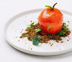 incomum sobremesa dentro a forma do uma tomate em uma branco prato foto