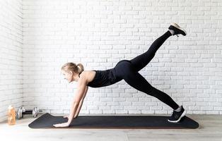 mulher em roupa esportiva preta fazendo flexões em casa foto