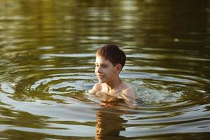 menino feliz se divertindo nadando na água foto