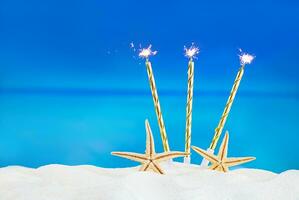 estrelas do mar com dourado velas com fogo em arenoso de praia com mar. aniversário, Natal, Novo ano. feriado dentro quente países. cópia de espaço foto