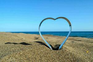 uma coração em forma metal escultura em a de praia foto