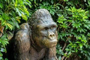 uma estátua do uma gorila sentado dentro a meio do uma jardim foto