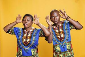 africano americano casal enganar por aí e mostrando boba careta juntos retrato. alegre homem e mulher par tendo diversão, posando com quadrinho face expressão e olhando às Câmera foto