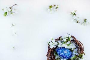 ninho com Páscoa ovos e galhos do Primavera floração cerejas em uma branco de madeira fundo. centeio ovos pintado com natural corantes. foto