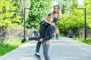 a menina abraço a cara a partir de atrás. feliz casal em uma andar. a menina obrigado para a presente. foto