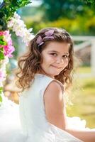 emocional pequeno menina dentro vestir posando com flores foto