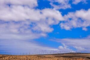 uma vento Fazenda dentro a deserto com nuvens dentro a céu foto