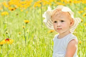 retrato do lindo pequeno menina em fundo do amarelo flores dentro uma Prado. feliz infância dentro natureza. caminhando enquanto quarentena longe a partir de pessoas foto