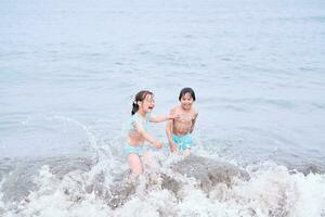 uma Garoto e uma menina estão tendo Diversão jogando dentro a mar. foto