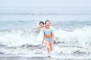 uma Garoto e uma menina estão tendo Diversão jogando dentro a mar. foto