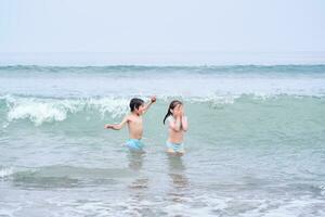 uma Garoto e uma menina estão tendo Diversão jogando dentro a mar. foto