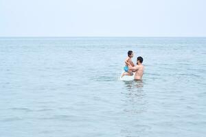 Papai tocam com dele filhos dentro a mar. foto