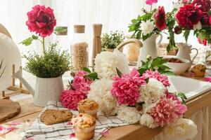 a cozinha bancada é decorado com peônias. a interior é decorado com Primavera flores Rosa peônias e doce bolos de copo em uma de madeira bancada. interior detalhes. foto