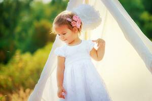 uma pequeno menina é em pé de a branco cabana para natureza foto