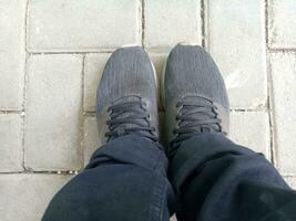 uma par do Preto sapatos em tijolo pavimentação, vestindo Preto calça, fotografado a partir de acima foto