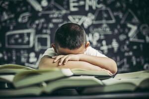 um menino de óculos estudando e sonolento. foto