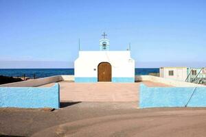 uma pequeno capela com uma azul porta e uma Cruz em a frente foto