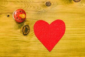 Rosa coração em uma de madeira mesa com chupeta foto
