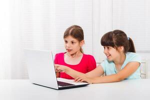 fofa pequeno meninas estão sentado e usando computador portátil. foto