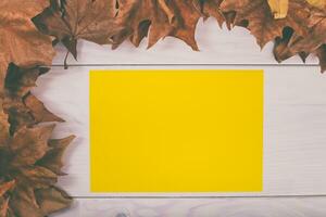 amarelo papel dentro outono folhas em branco de madeira fundo foto