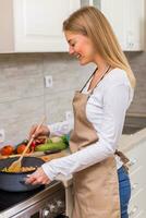 lindo mulher cozinhando refeição dentro dela cozinha foto