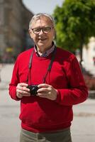 Senior homem turista goza fotografando às a cidade foto