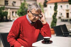 triste Senior homem sentado sozinho às a Barra foto