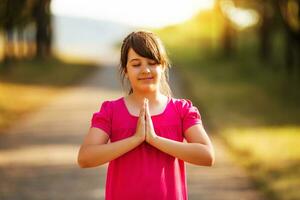 lindo pequeno menina meditando dentro natureza foto