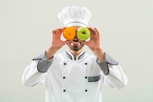 chefe de cozinha é tendo Diversão com fruta em cinzento fundo foto