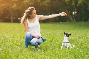 lindo mulher goza jogando com dela fofa cachorro jack russell terrier dentro a natureza. foto